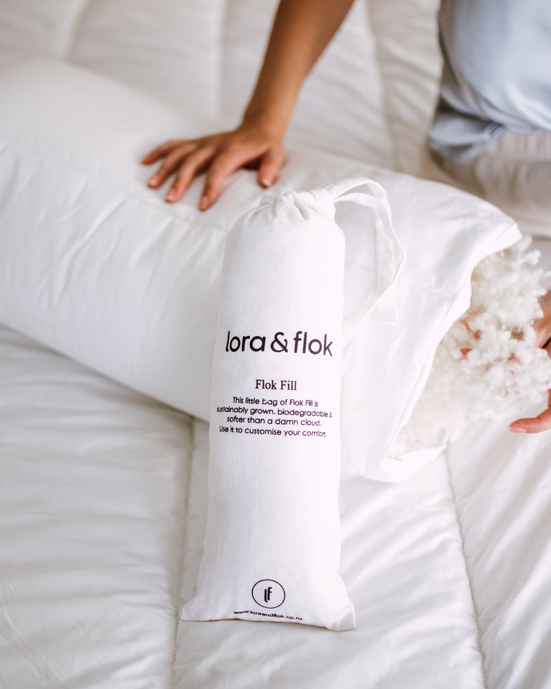 Lady adding more Flok Fill to her adjustable pillow made from New Zealand wool by Lora & Flok.